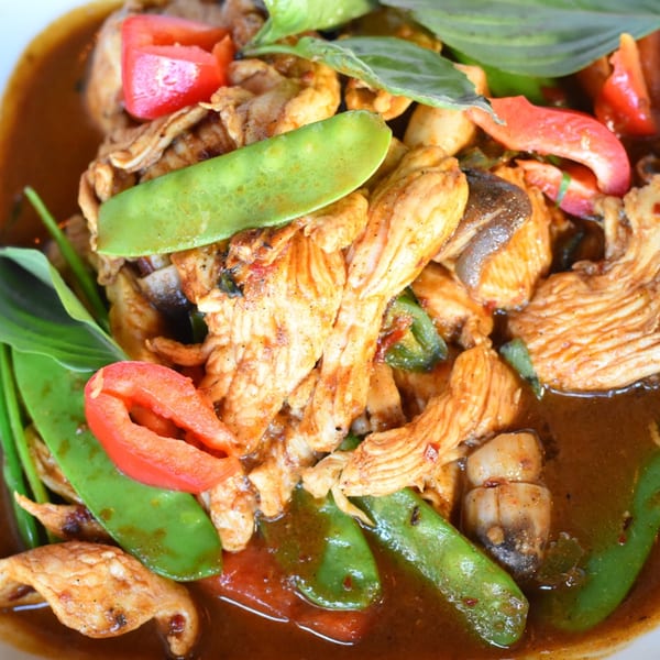 Chicken stir-fry with snow peas, red bell peppers, and basil in a rich brown sauce.